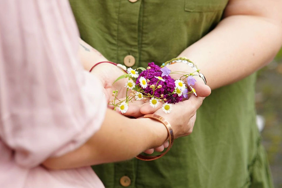 Frauenhände halten gemeinsam Blumen Frauenhände halten gemeinsam Blumen
